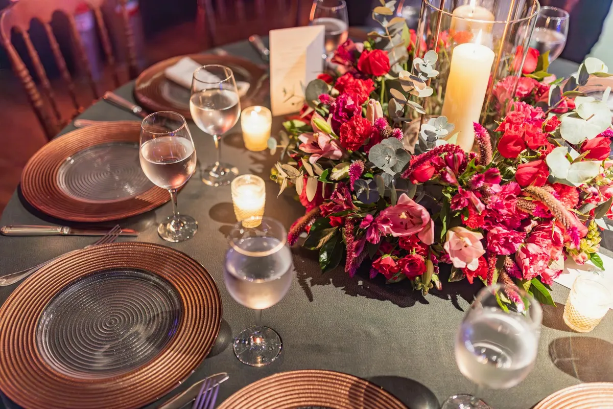 An elegant dinner party table set with candles, flowers, and warm light
